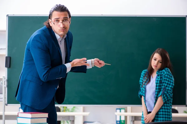 Young handsome teacher and female student in the classroom — Stock Photo, Image