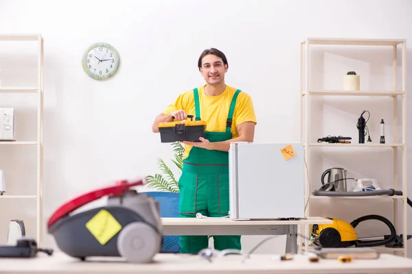 Man repairman repairing vacuum cleaner and fridge