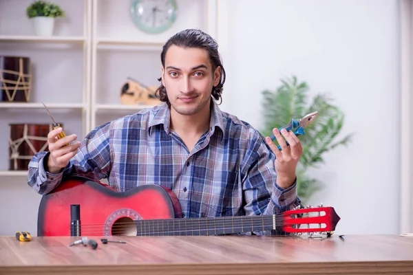 Joven guapo reparador reparación de la guitarra —  Fotos de Stock