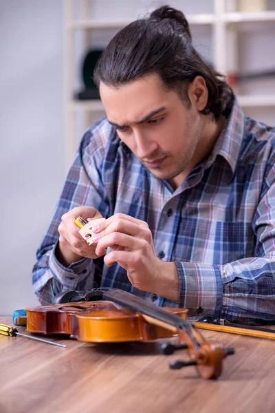 Junger gutaussehender Reparateur repariert Geige — Stockfoto