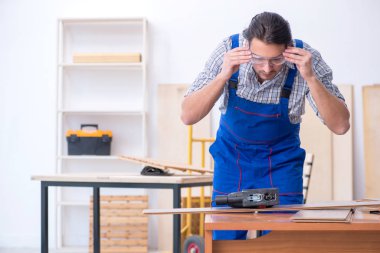 Genç erkek marangoz içeride çalışıyor.