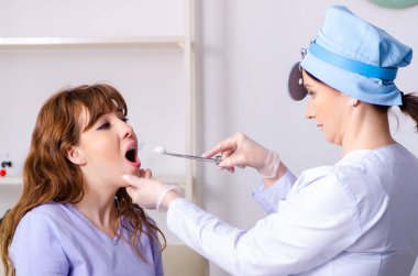 Kadın doktor otolaringolojisti ziyaret eden genç bir kadın.