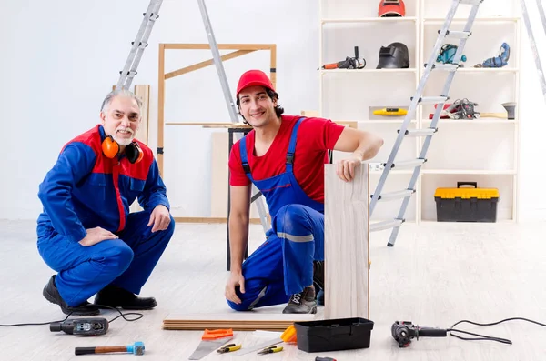 Two professional contractors laying flooring at home