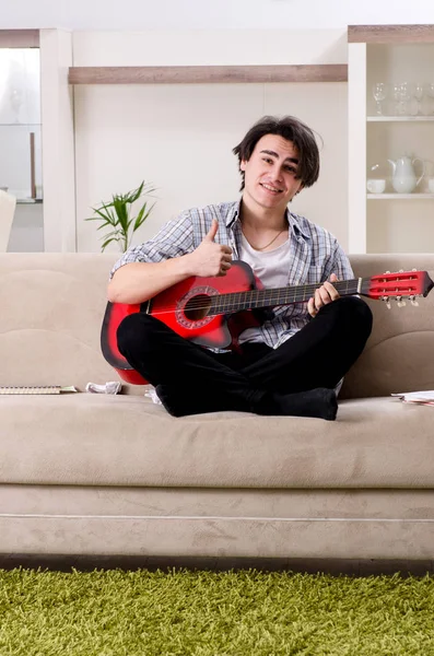 Jovem com guitarra em casa — Fotografia de Stock