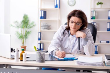 Klinikte çalışan yaşlı bir kadın doktor.