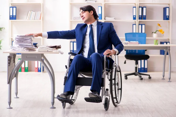 Jovem funcionário do sexo masculino em cadeira de rodas que trabalha no escritório — Fotografia de Stock