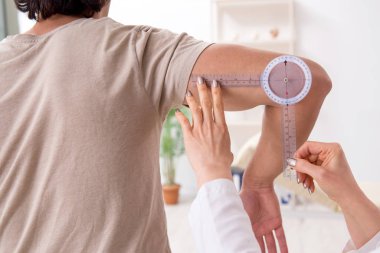 Kadın doktor hastaları goniyometre ile kontrol ediyor.