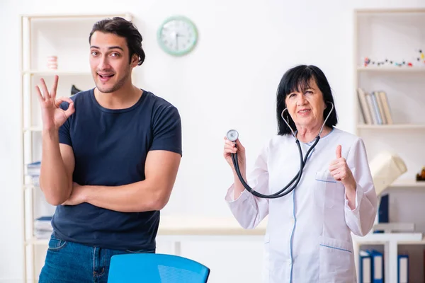 Ung manlig patient besöker äldre kvinnlig läkare — Stockfoto