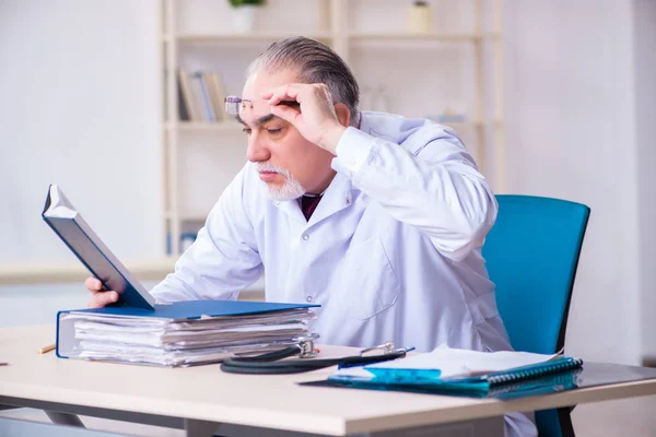 Gammal manlig läkare som arbetar på kliniken — Stockfoto