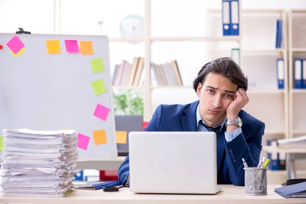 Joven empleado masculino infeliz con el trabajo excesivo — Foto de Stock