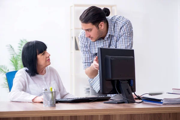 Junge männliche Mitarbeiter erklären alten Kolleginnen, wie sie zu uns kommen — Stockfoto