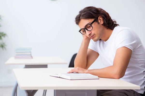 Giovane studente maschio seduto in classe — Foto Stock