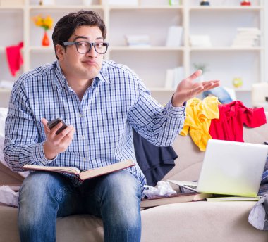 Genç adam dağınık bir odada çalışıyor.