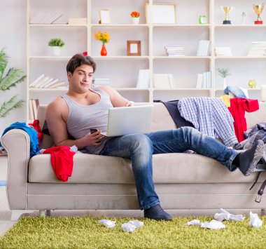 Genç adam dağınık bir odada çalışıyor.