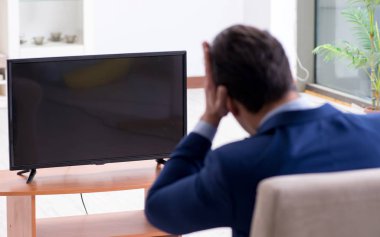 İş adamı ofiste televizyon izliyor.