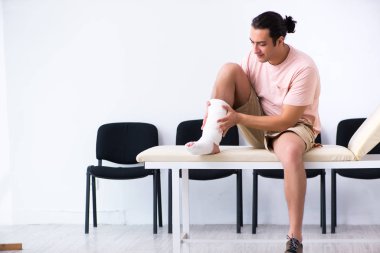 Genç yaralı adam hastane koridorunda sırasını bekliyor.