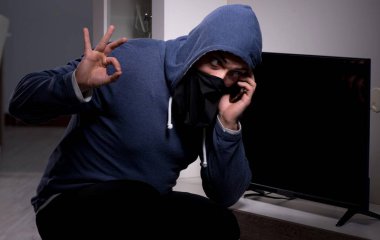 Hırsız, apartmandan televizyon çalıyor.