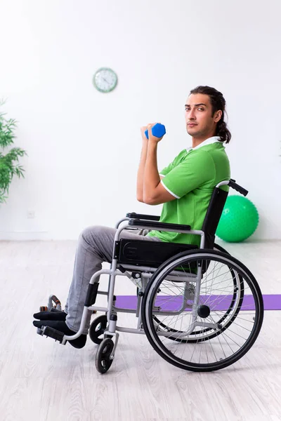 Jovem em cadeira de rodas fazendo exercícios dentro de casa — Fotografia de Stock
