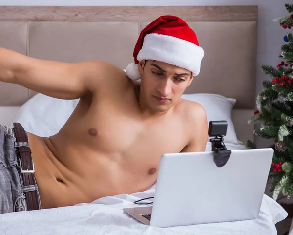 Sexy man in het bed het dragen van santa hoed in kerst concept — Stockfoto