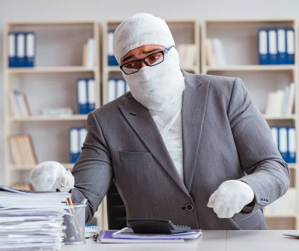 Bandaged businessman worker working in the office doing paperwor — Stock Photo, Image