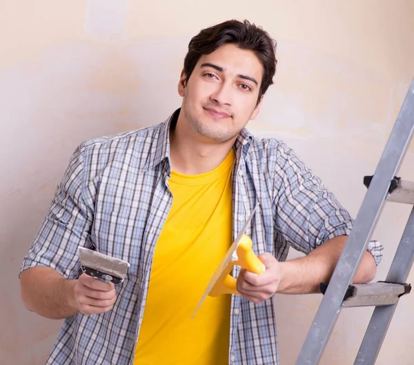 Hombre joven aplicando yeso en la pared en casa — Foto de Stock