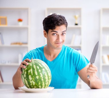 Evde karpuz yiyen bir adam.