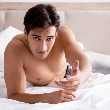 Genç yakışıklı gömleksiz adam gösteren çıplak gövde seksi yatakta s