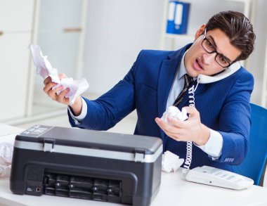 Businessman angry at copying machine jamming papers clipart