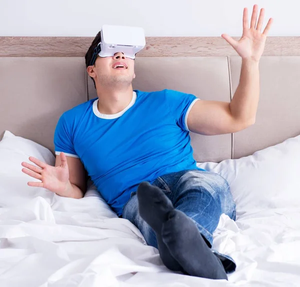 Jovem na cama vestindo um vr realidade virtual head set — Fotografia de Stock