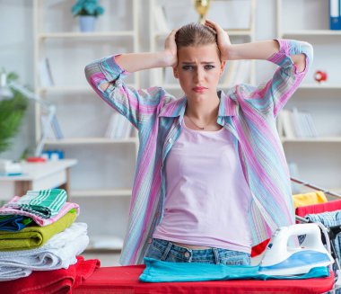 Üzücü kadın evde kıyafetleri ütülüyor.