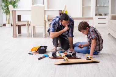 Genç baba oğluyla kaykay tamir ediyor.