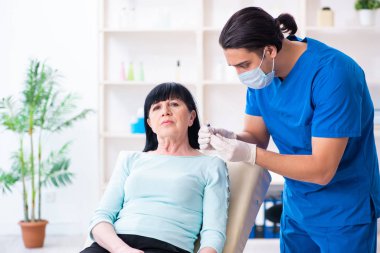 Yaşlı kadın estetik ameliyat için erkek doktoru ziyaret ediyor.