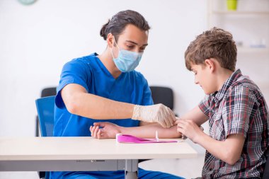 Genç çocuk hastanede doktoru ziyaret ediyor.