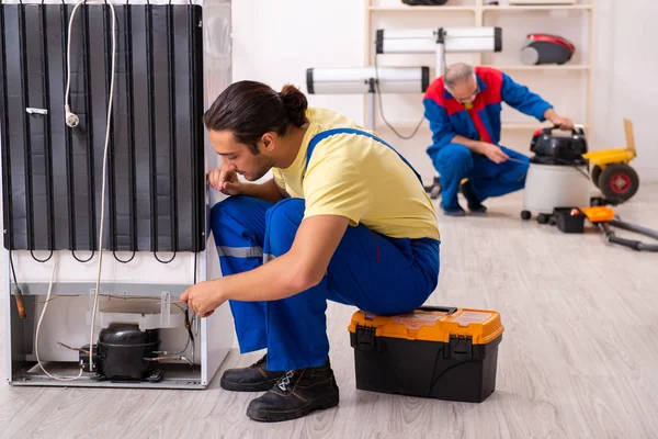 Zwei Bauunternehmer reparieren Kühlschrank in Werkstatt — Stockfoto