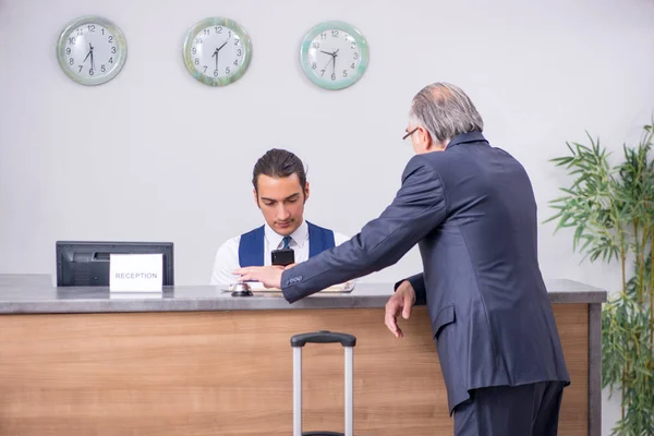 Oude zakenman bij de hotelreceptie — Stockfoto