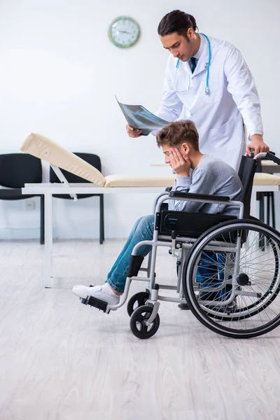 Молодий чоловік лікар педіатр і хлопчик в інвалідному кріслі — стокове фото
