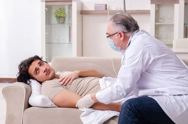 Velho médico visitando jovem paciente masculino — Fotografia de Stock