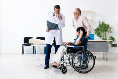 Yaşlı çift genç erkek doktoru ziyaret ediyor.