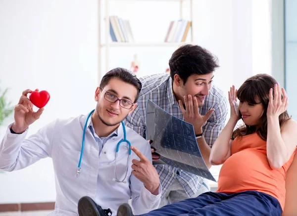 Mujer embarazada con su marido visitando al médico en la clínica —  Fotos de Stock