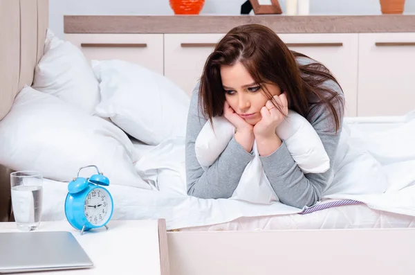 Mujer joven acostada en la cama en concepto de gestión del tiempo — Foto de Stock