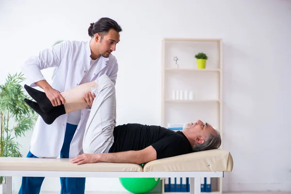 Vecchio ferito visitando giovane medico — Foto Stock