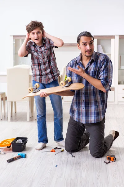 Young father repairing skateboard with his son at home