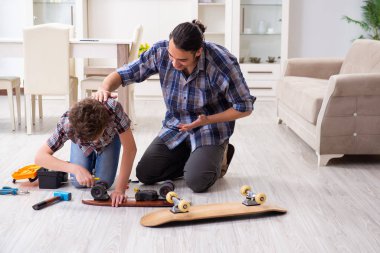 Genç baba oğluyla kaykay tamir ediyor.