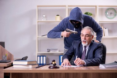 Genç gangster yaşlı yargıcı tehdit ediyor.