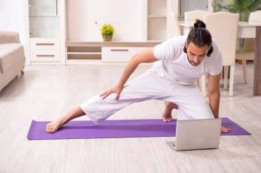 Genç adam evde fiziksel egzersiz yapıyor.