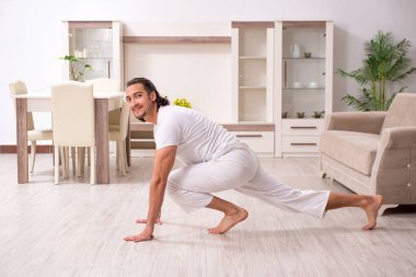 Genç adam evde fiziksel egzersiz yapıyor.
