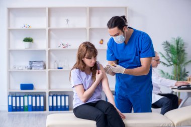 İki doktor genç kadını muayene ediyor.