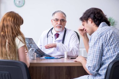 Genç çift yaşlı erkek doktoru ziyaret ediyor.