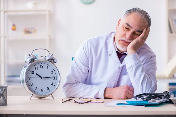 Old male doctor working in the clinic — Stock Photo, Image