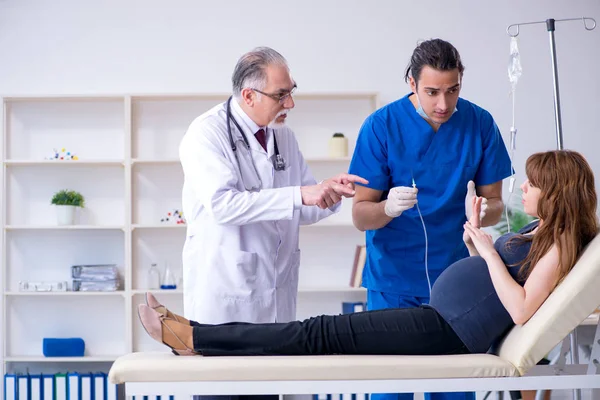 Dois médicos examinando jovem mulher — Fotografia de Stock